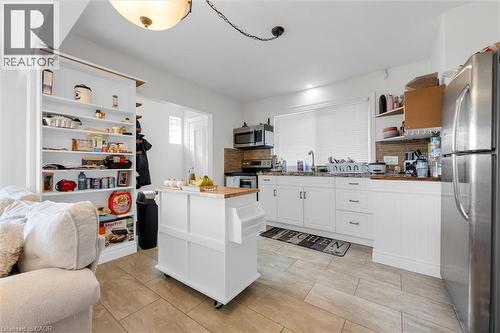 Kitchen featuring white cabinetry, a stainless steel refrigerator, tile flooring, a window with blinds, and a built-in shelving unit - 406 East 43Rd Street, Hamilton, ON - Indoor Photo Showing Kitchen