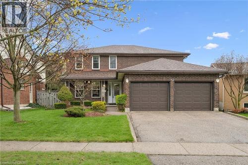 Brick exterior residence featuring a covered front porch, a two-car attached garage, a paved driveway, a manicured lawn, and established perimeter landscaping - 42 Trailview Drive, Kitchener, ON - Outdoor