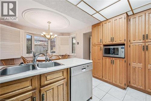 Kitchen featuring a double basin stainless steel sink, wood cabinetry, white countertops, built-in microwave, and a bay window with plantation shutters - 42 Trailview Drive, Kitchener, ON - Indoor Photo Showing Kitchen With Double Sink