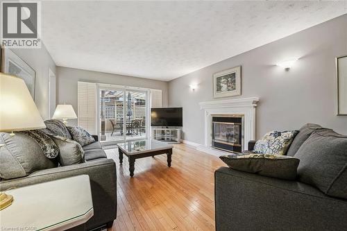 Living area featuring wood-finish flooring, a white mantel fireplace, and wall sconces - 42 Trailview Drive, Kitchener, ON - Indoor Photo Showing Living Room With Fireplace