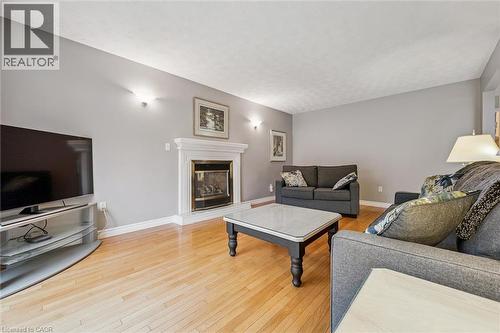 Living area featuring wood-finish flooring, a white mantel fireplace, and light gray wall paint - 42 Trailview Drive, Kitchener, ON - Indoor Photo Showing Living Room With Fireplace