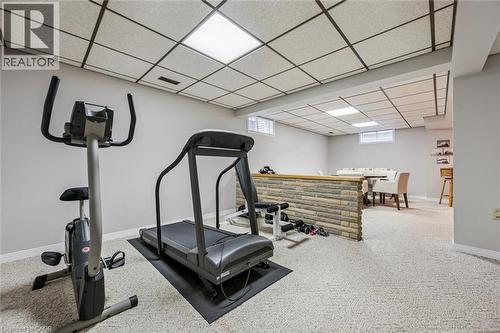Lower level recreation space featuring light-colored carpeting, a drop ceiling with recessed lighting, and a partial stone-clad wall - 42 Trailview Drive, Kitchener, ON - Indoor Photo Showing Gym Room