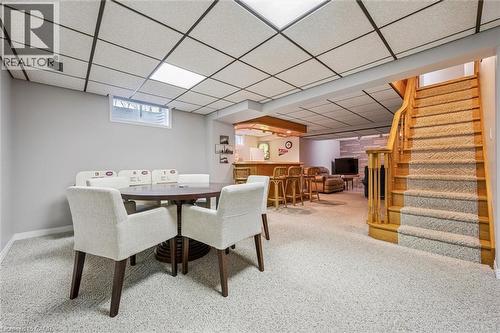 Carpeted lower level featuring a built-in bar with wood-finish accents, drop ceiling with recessed lighting, and a staircase with wood-finish handrails - 42 Trailview Drive, Kitchener, ON - Indoor