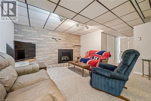 Recreation room featuring a gas fireplace with a black surround, a stacked stone accent wall, and recessed track lighting - 42 Trailview Drive, Kitchener, ON - Indoor Photo Showing Other Room With Fireplace