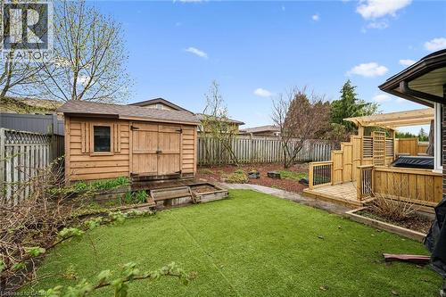 Spacious backyard featuring artificial turf, a wood-sided storage shed, a multi-level wood deck with a pergola, and perimeter fencing - 42 Trailview Drive, Kitchener, ON - Outdoor