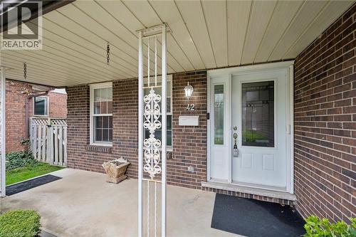 Covered front porch featuring a white screen door, decorative side window, and sconce lighting - 42 Trailview Drive, Kitchener, ON - Outdoor With Exterior