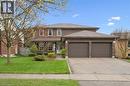 Brick exterior residence featuring a covered front porch, a two-car attached garage, a paved driveway, a manicured lawn, and established perimeter landscaping - 42 Trailview Drive, Kitchener, ON  - Outdoor 