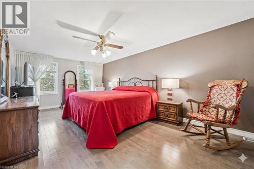Spacious bedroom featuring wood-finish flooring, two large windows with sheer white drapes, a ceiling fan with integrated lighting, and neutral wall tones - 42 Trailview Drive, Kitchener, ON - Indoor Photo Showing Bedroom