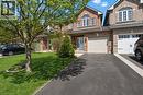 Brick facade home featuring a single-car garage, arched window, paved driveway, and manicured front lawn with mature tree - 62 Moore Crescent, Ancaster, ON  - Outdoor With Facade 