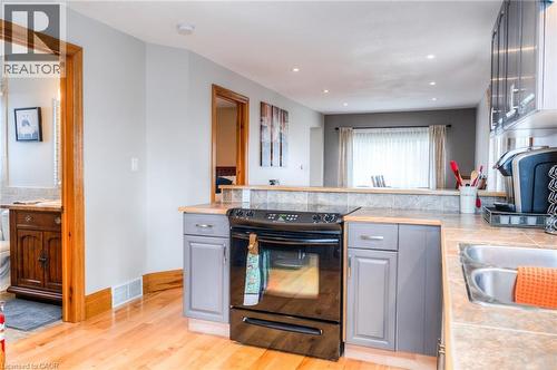 Kitchen featuring hardwood flooring, gray cabinetry, black range, stainless steel sink, and wood-finish countertops - 46 2 Avenue, Kitchener, ON - Indoor Photo Showing Kitchen With Double Sink