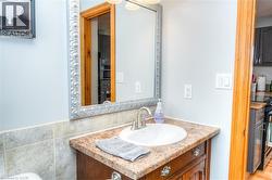 Powder room featuring a decorative framed mirror, single vanity with an integrated sink, and a tiled backsplash - 