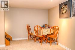 Carpeted room with recessed lighting, light beige wall paint, white baseboards, and a visible stairwell with wood trim - 
