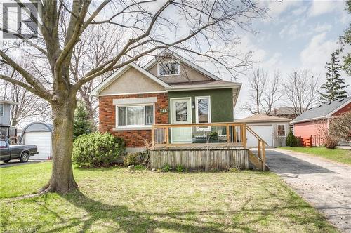 Two-story residence featuring a brick and stucco facade, a full-width front deck with glass panels, a detached garage, and a paved driveway - 46 2 Avenue, Kitchener, ON - Outdoor