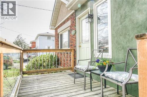 Front entry deck featuring wood-finish flooring, a wood-and-glass railing system, and a brick-and-stucco exterior facade - 46 2 Avenue, Kitchener, ON - Outdoor With Exterior