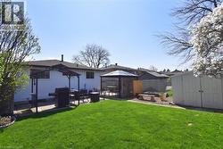 Expansive backyard featuring a green lawn, two distinct patio areas, and a spacious storage shed with double doors - 
