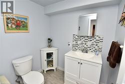 Bathroom featuring a white vanity with integrated sink, a mosaic tile backsplash, and light gray wall paint - 