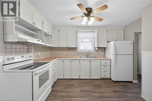 Kitchen featuring white cabinetry, tile countertops, a white electric range, a white refrigerator, and wood-finish flooring - 192 Ivon Avenue, Hamilton, ON - Indoor Photo Showing Kitchen With Double Sink