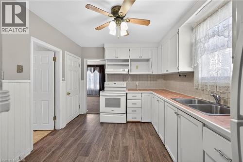 Kitchen featuring white cabinetry, wood-finish flooring, a double basin stainless steel sink, and a white electric range - 192 Ivon Avenue, Hamilton, ON - Indoor Photo Showing Kitchen With Double Sink
