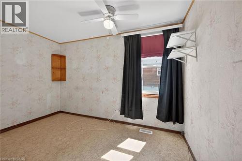 Room featuring patterned wallpaper, a ceiling fan with integrated lighting, and a single window with dark drapery - 192 Ivon Avenue, Hamilton, ON - Indoor Photo Showing Other Room