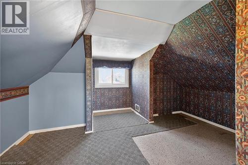 Attic space featuring a window, sloped ceilings, patterned wallpaper, wall-to-wall carpeting, and baseboard trim - 192 Ivon Avenue, Hamilton, ON - Indoor Photo Showing Other Room