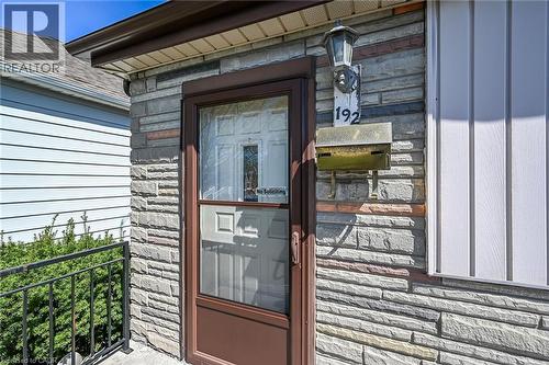 Stone veneer facade featuring a brown storm door and a traditional wall-mounted light fixture - 192 Ivon Avenue, Hamilton, ON - Outdoor