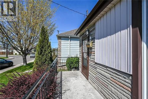 Concrete entryway with a metal railing, featuring stone veneer and vertical siding exterior finishes - 192 Ivon Avenue, Hamilton, ON - Outdoor