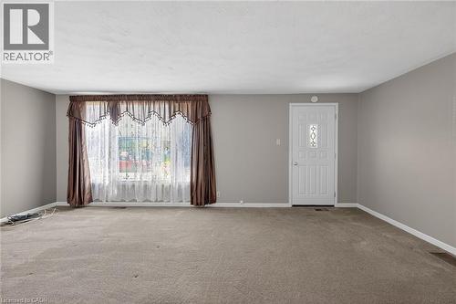 Spacious room featuring carpeting, light gray wall paint, and a large front window with a decorative valance - 192 Ivon Avenue, Hamilton, ON - Indoor Photo Showing Other Room