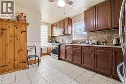 Kitchen featuring extensive dark wood cabinetry, a tile backsplash, and a ceiling fan with integrated lighting - 