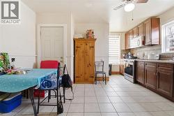 Kitchen featuring a full suite of appliances, wood-finish cabinetry, tile flooring, and a ceiling fan - 