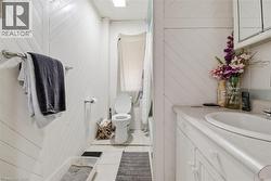 Bathroom featuring shiplap wall paneling, a white vanity with an integrated sink, a wall-mounted medicine cabinet, and tile flooring - 