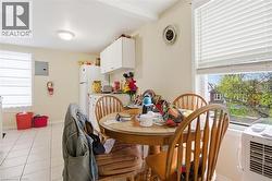 Kitchen area featuring white cabinetry, white appliances, and tiled flooring - 