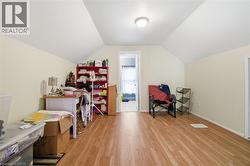 Attic room featuring wood-finish flooring, neutral-toned walls, and a recessed ceiling light - 