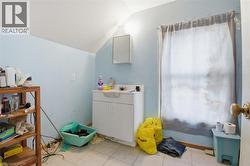 Tiled flooring in a room featuring a vanity with storage, a wall-mounted medicine cabinet, and a window with a curtain - 