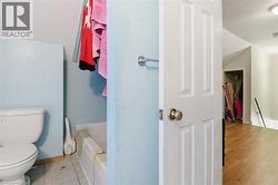Bathroom featuring a white toilet, light blue wall paint, and white bathtub with tiled surround - 