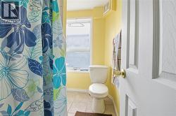 Bathroom with a white toilet, tile flooring, and yellow walls - 