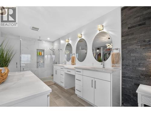 Spa-inspired ensuite with dual vanities and a beautifully tiled shower featuring a rain head. - 3859 Carrall Road, West Kelowna, BC 