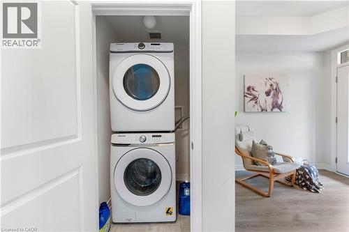 Dedicated laundry closet featuring a stacked white washer and dryer unit, overhead lighting, and light wood-finish flooring - 50 Hollywood Court, Cambridge, ON - Indoor Photo Showing Laundry Room