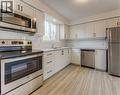 Bright kitchen featuring stainless steel appliances, white shaker-style cabinetry, light wood-finish flooring, white subway tile backsplash, and a double basin sink beneath a window - 40 Daniel Avenue Unit# 2, Kitchener, ON  - Indoor Photo Showing Kitchen With Stainless Steel Kitchen With Double Sink 