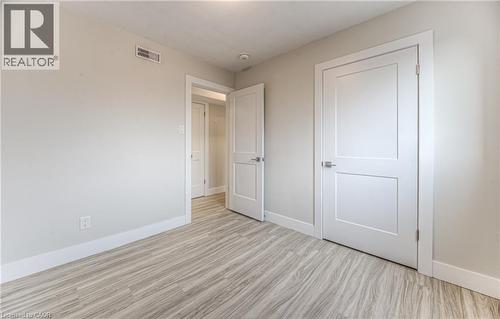 Light wood-finish flooring complements the neutral wall color - 40 Daniel Avenue Unit# 2, Kitchener, ON - Indoor Photo Showing Other Room