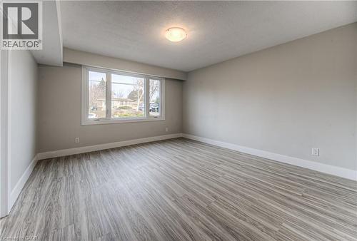 Spacious room with wood-finish flooring, a large multi-pane window, neutral wall tones, and white trim - 40 Daniel Avenue Unit# 2, Kitchener, ON - Indoor Photo Showing Other Room