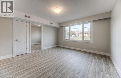 Spacious room featuring wood-finish flooring, ample natural light from a large window, a classic two-panel door, and a flush mount ceiling light fixture - 40 Daniel Avenue Unit# 2, Kitchener, ON - Indoor Photo Showing Other Room