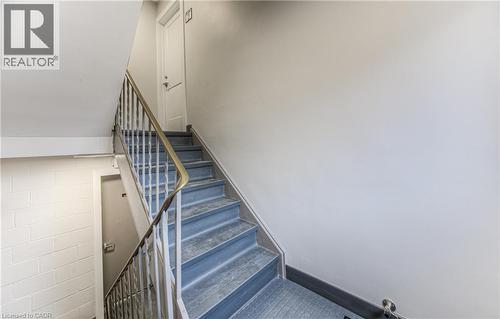 Stairwell featuring metal railings, light gray walls, and blue-toned stair treads - 40 Daniel Avenue Unit# 2, Kitchener, ON - Indoor Photo Showing Other Room
