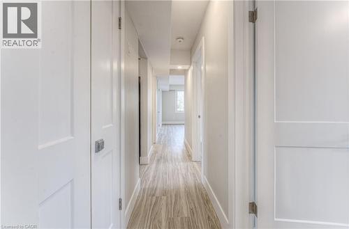 Hallway featuring wood-finish flooring, white panel doors with brushed nickel hardware, recessed ceiling lighting, and light-toned walls - 40 Daniel Avenue Unit# 2, Kitchener, ON - Indoor Photo Showing Other Room