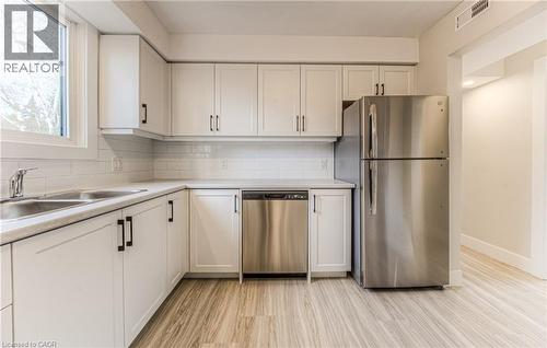 Kitchen featuring white shaker-style cabinetry with dark hardware, a stainless steel double-basin sink, and a white subway tile backsplash - 40 Daniel Avenue Unit# 2, Kitchener, ON - Indoor Photo Showing Kitchen With Stainless Steel Kitchen With Double Sink