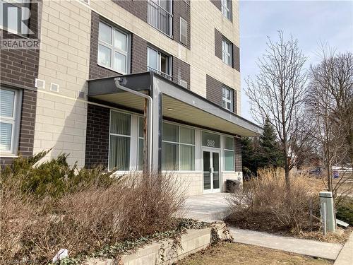 Building entrance featuring a contemporary awning, large glass doors, and surrounding low-maintenance landscaping - 392 Albert Street Unit# 302, Waterloo, ON - Outdoor