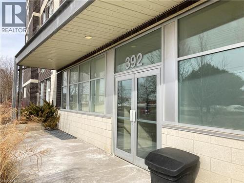 Building entrance featuring glass double doors, large storefront windows, and a protective overhead canopy with recessed lighting - 392 Albert Street Unit# 302, Waterloo, ON - Outdoor With Exterior