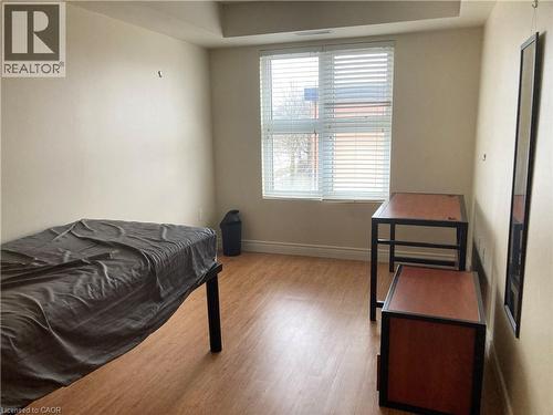 Room featuring wood-finish flooring, a window with horizontal blinds, and neutral-toned walls - 392 Albert Street Unit# 302, Waterloo, ON - Indoor