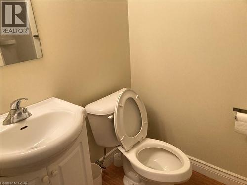 Bathroom featuring a white toilet, coordinating vanity with integrated sink, chrome faucet, and wood-finish flooring - 392 Albert Street Unit# 302, Waterloo, ON - Indoor Photo Showing Bathroom