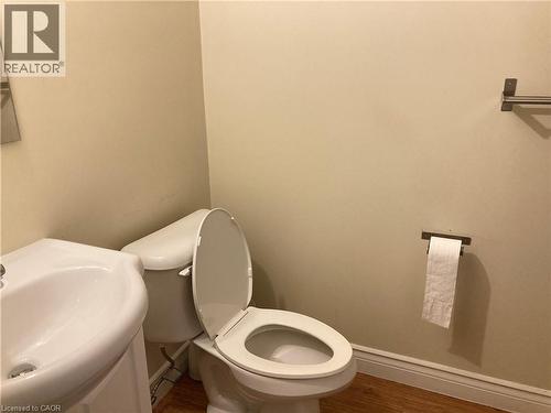 Hardwood-style flooring complementing a white pedestal sink and toilet - 392 Albert Street Unit# 302, Waterloo, ON - Indoor Photo Showing Bathroom