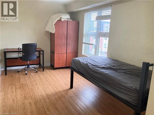 Well-lit room featuring wood-finish flooring and a large window with horizontal blinds - 392 Albert Street Unit# 302, Waterloo, ON - Indoor Photo Showing Bedroom
